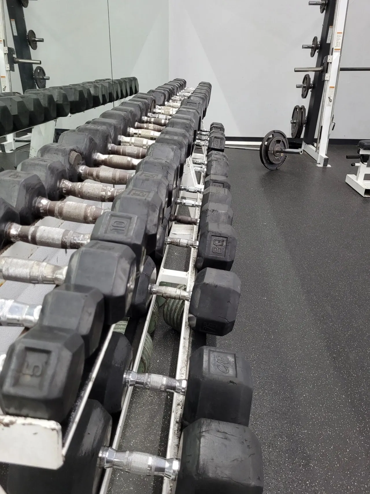 A rack of dumbbells reflected in the gym mirror